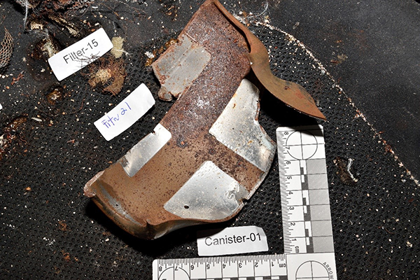 Airbag inflators house the propellant which turns into the gas that fills an airbag when triggered. This is an example of a ruptured passenger’s side inflator. Also pictured is metal filter material on the passenger’s seat.