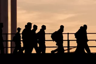 Dark silhouettes of people walking across a bridge