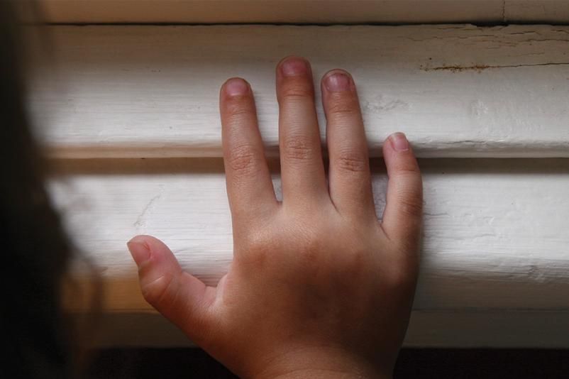 Image of a child's hand on a painted windowsill