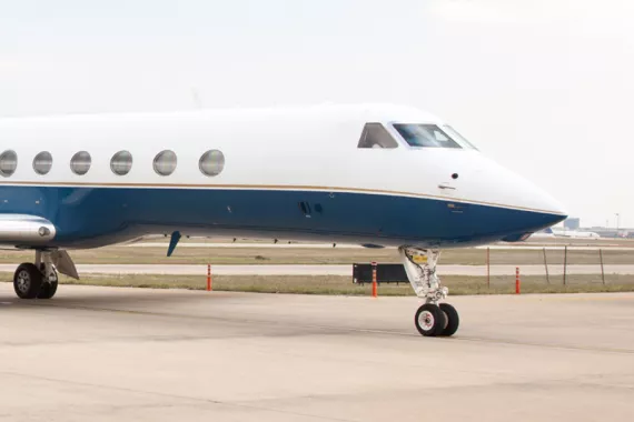 A blue and white Gulfstream airplane sits on a tarmac at an airport