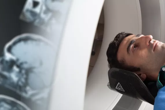 A man's head enters an MRI machine from the lower right corner of the image.
