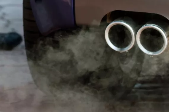 Close-up view of a car's exhaust pipes releasing visible clouds of emissions