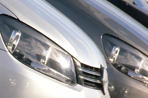 Close-up of the front of a row of cars, prominently featuring their headlights