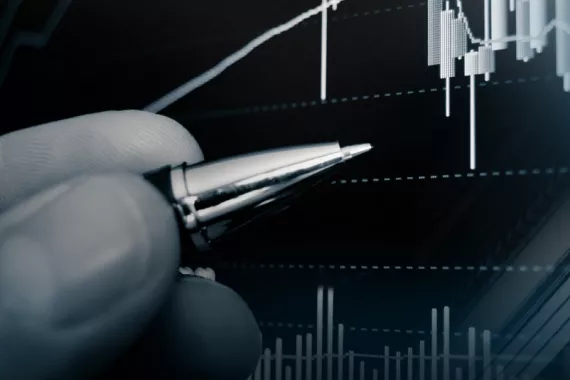 A graphic collage features a hand holding a pen that points to a stock market chart. In the background is an ornate Greek pillar.