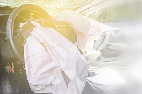 Deployed front airbags hang limply in a car.