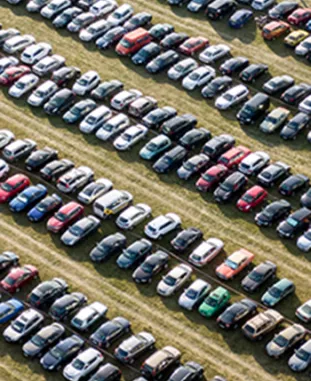 Ten diagonal rows of cars parked next to each other on a grassy field.