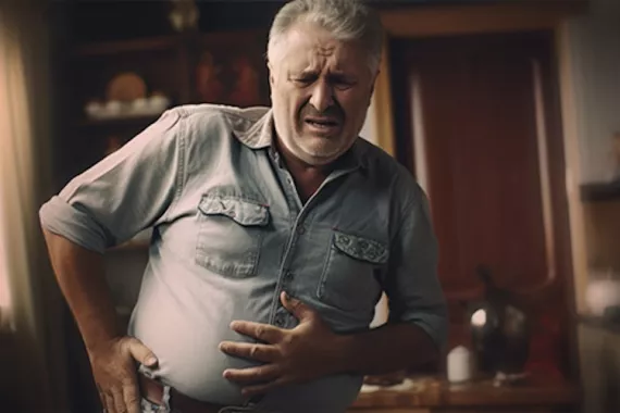A man is standing and has one hand on his belly and one hand placed above his hip