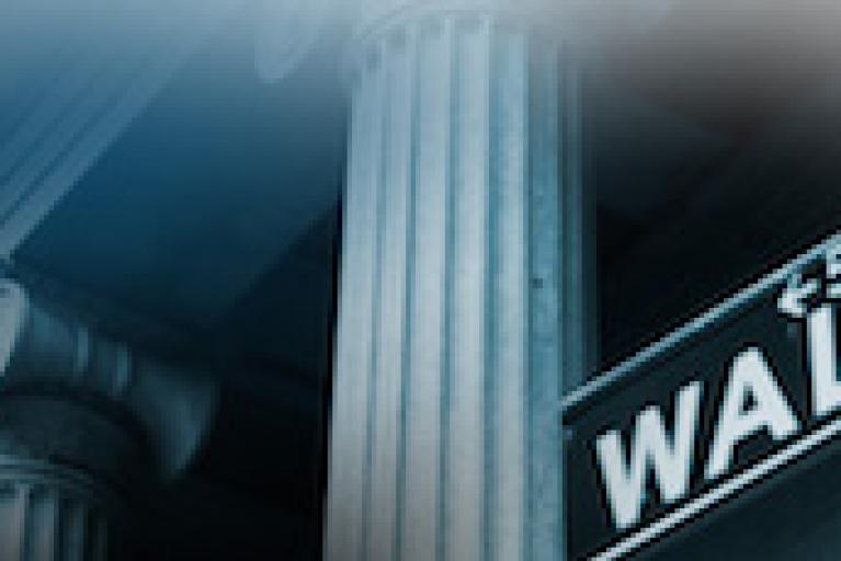 A Wall St. sign against a white collumed building. The sign has the number 55 and an arrow point to the left.