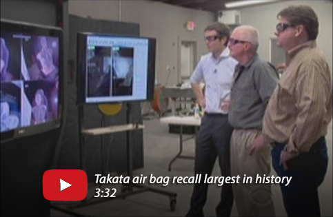 A screenshot showing three men in special glasses viewing images of airbags on TV monitors.